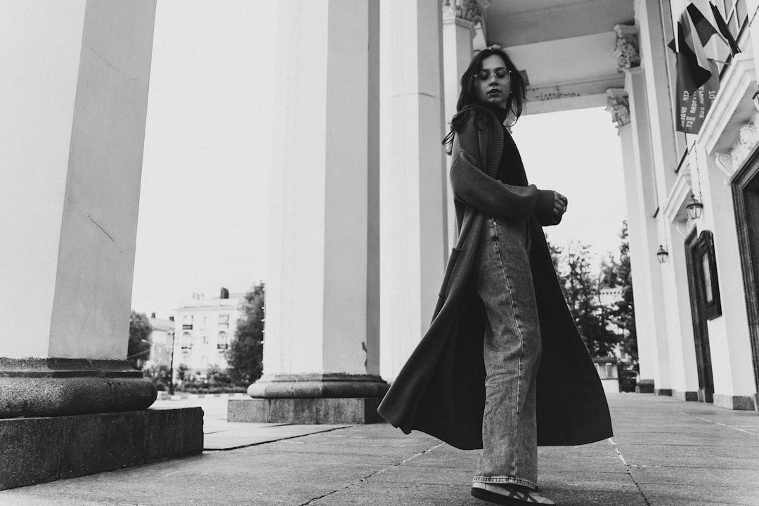 Vrouw in een donkere monochrome outfit bij klassieke zuilen